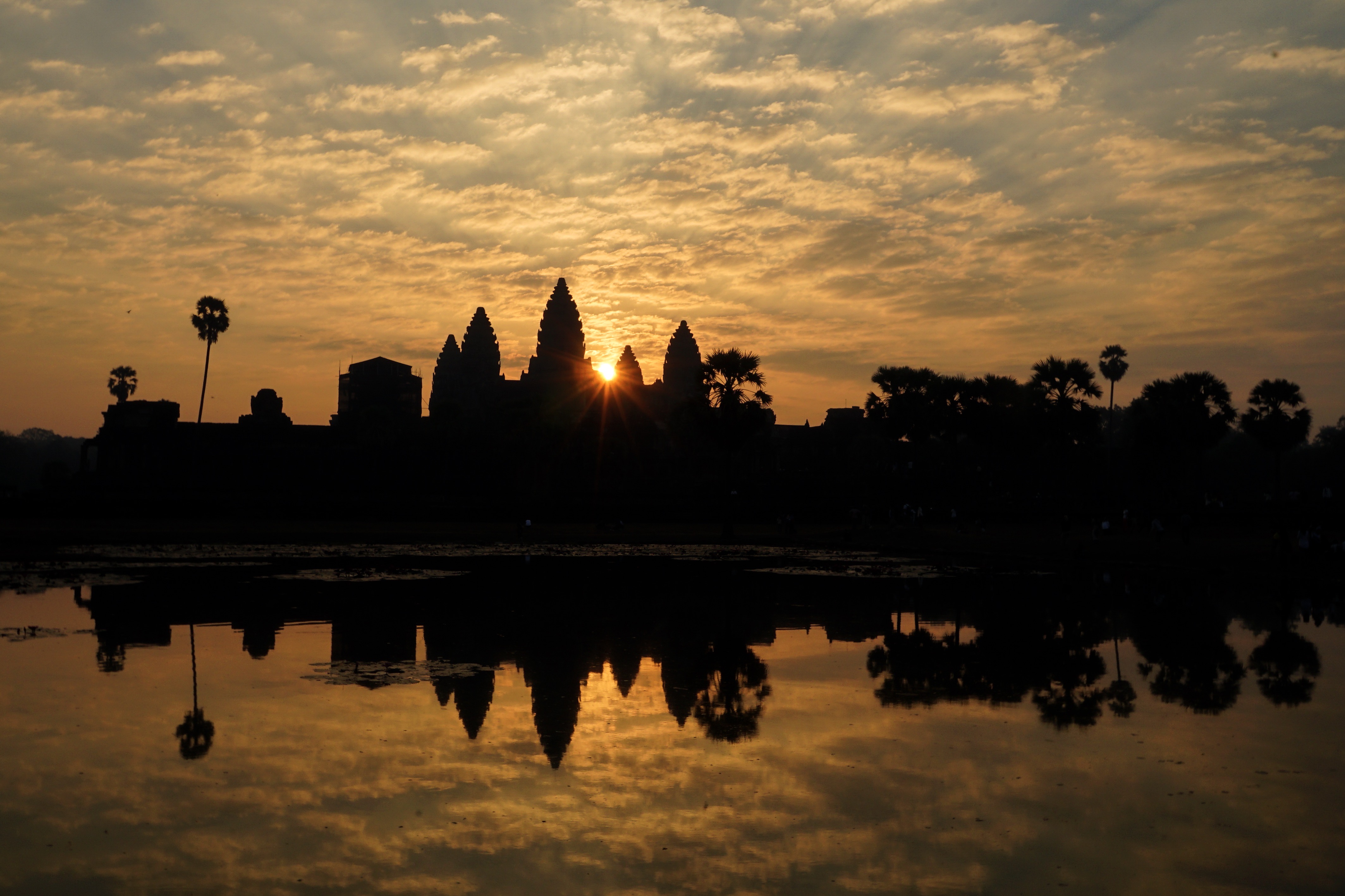 Angkor Wat silhouetted against a golden sunrise and reflected in water