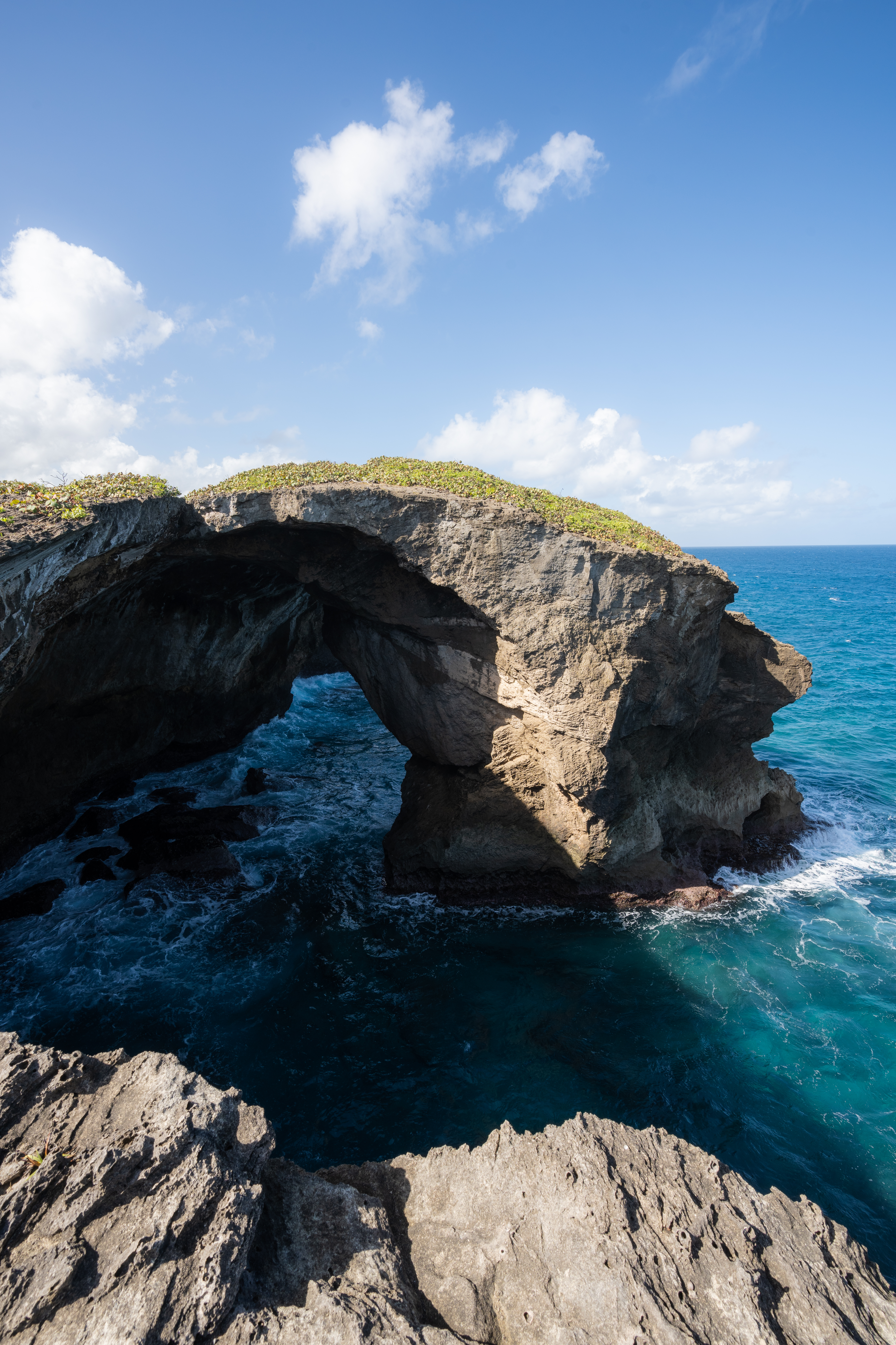 A natural rock bridge extending over bright blue ocean water