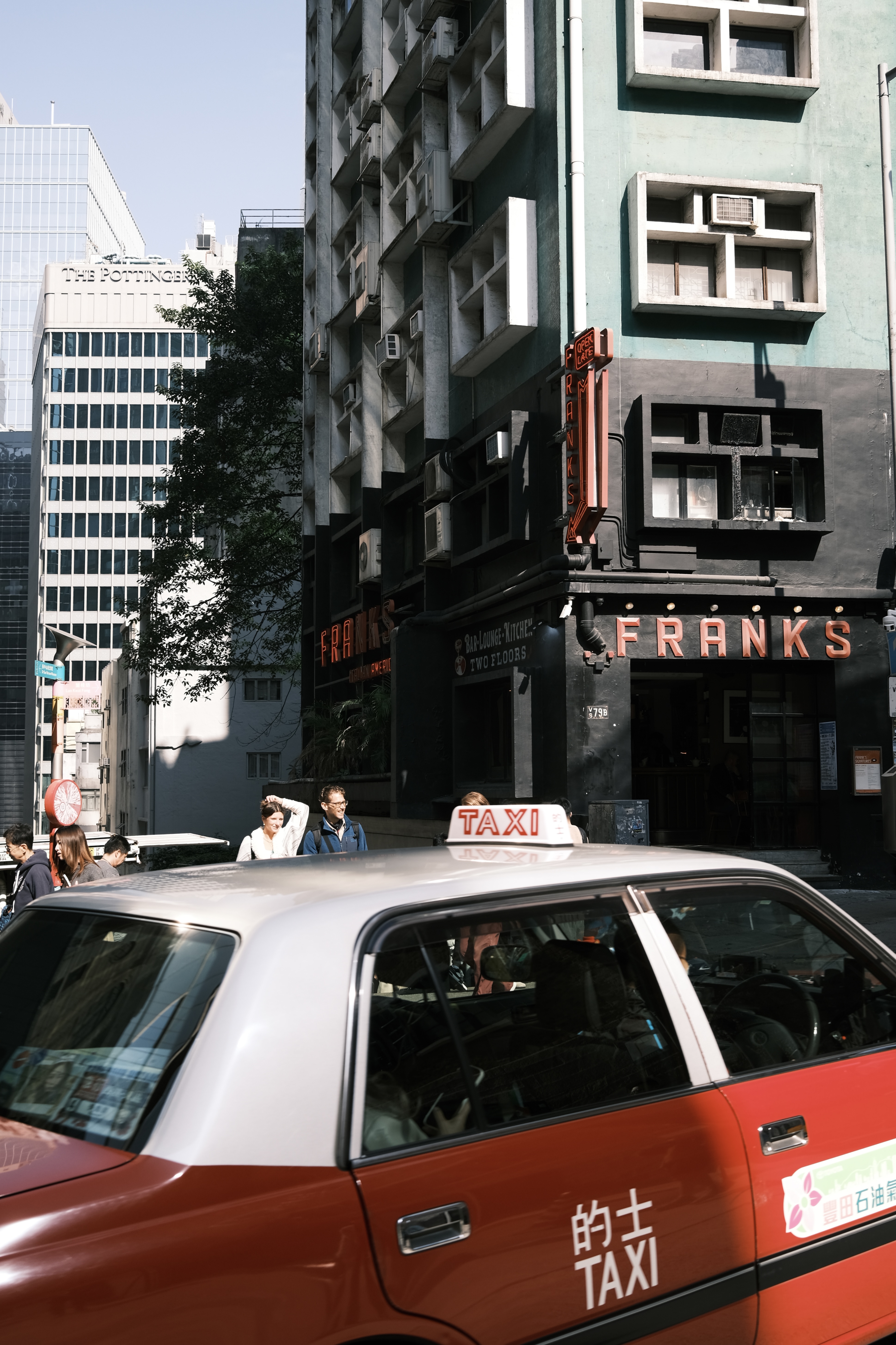 A red taxi passing through a busy city street