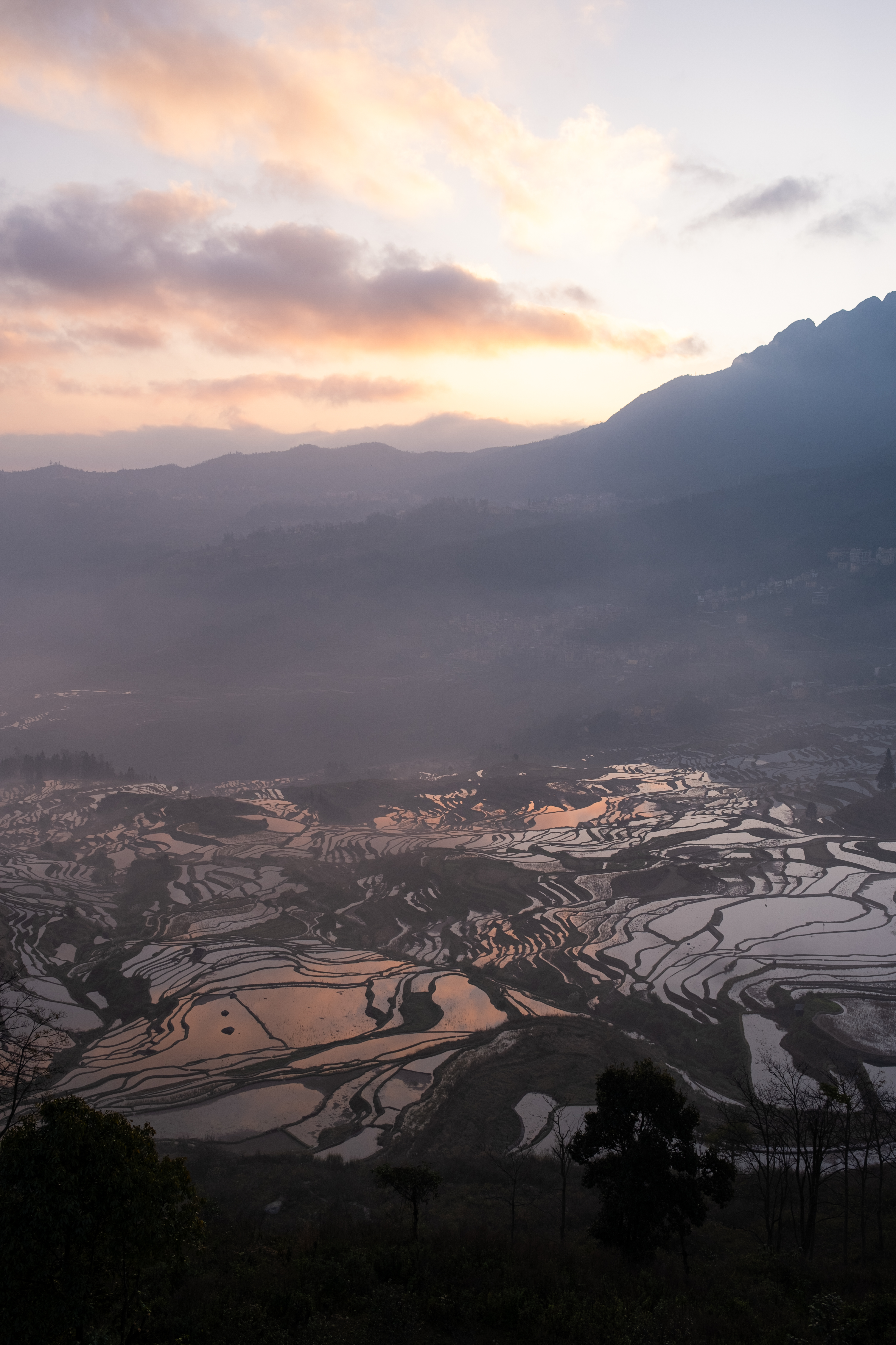 Terraced fields and a mountain village glowing at sunrise